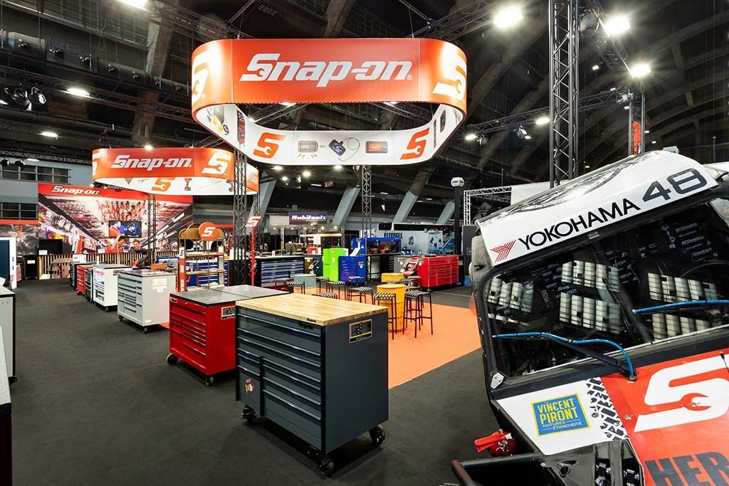 Snap-on stand at Autotechnica Brussels with tool cabinets, overhead ring banner and race car