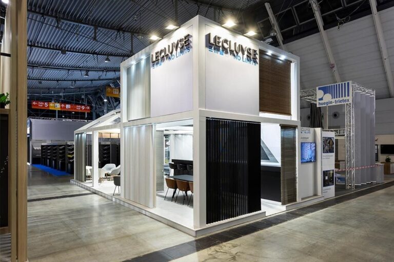 Two-storey white Lecluyse stand at R+T Stuttgart showing blinds and a seating area