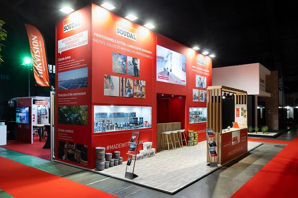 Red Soudal stand at Batibouw Brussels with product display niches and a timber bar