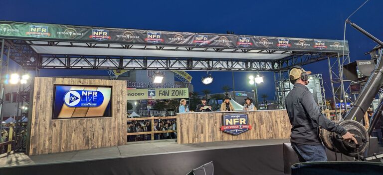 NFR Live broadcast stage with timber-clad desk, video screen and truss canopy at the National Finals Rodeo