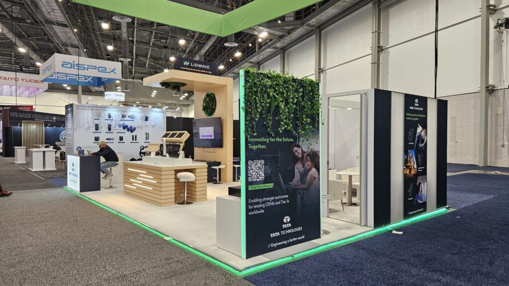 TATA Technologies stand at CES 2026 with timber-slat counter, green-lit floor edge and a hanging plant wall