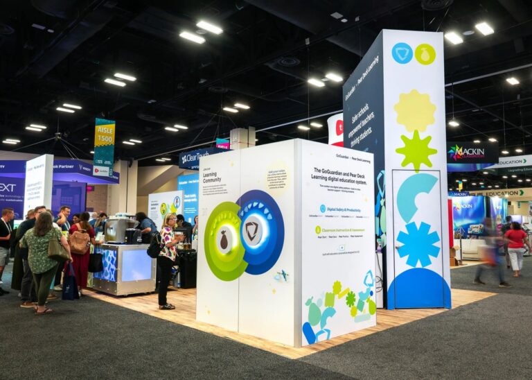 GoGuardian and Pear Deck Learning stand at ISTE with a white cube structure and tall graphic tower