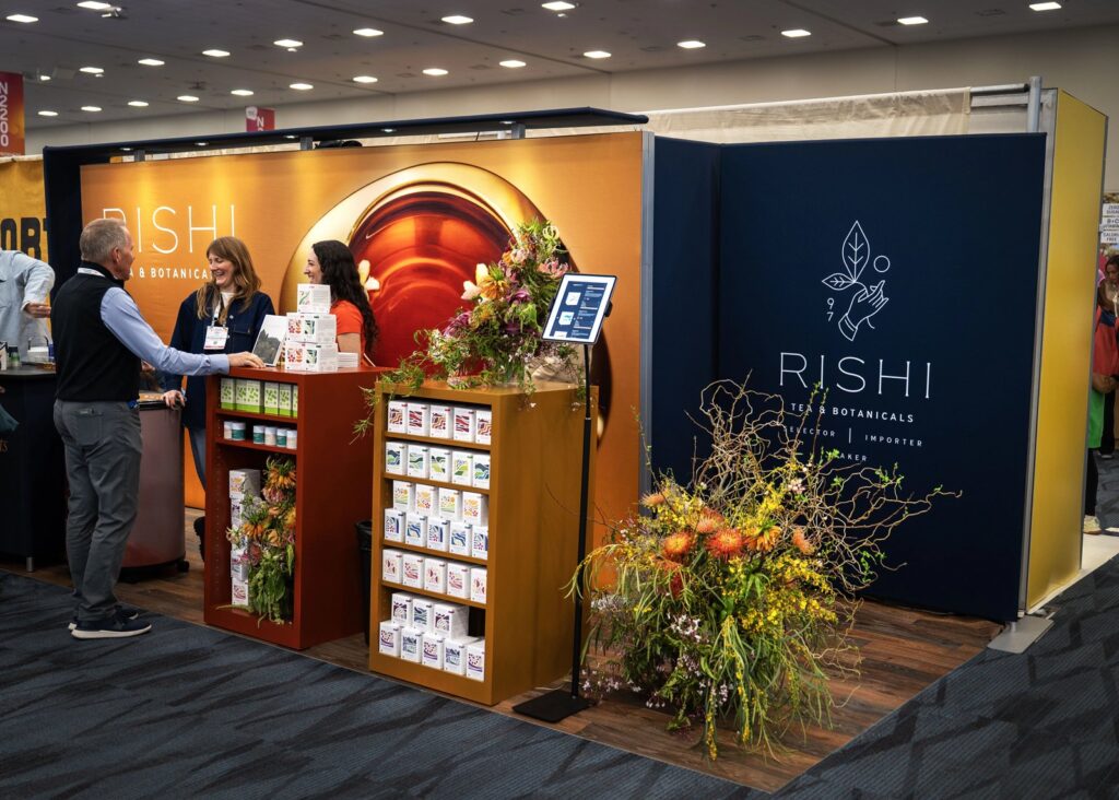 Rishi Tea & Botanicals inline stand at Expo West with backlit walls and product shelving