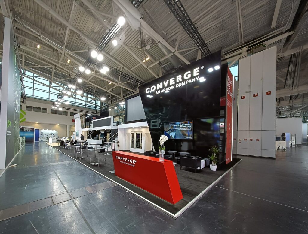 Black and red Converge stand with a raised meeting area, bar seating and lounge in a Munich exhibition hall